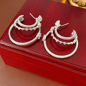 Macro detail of silver layered hoop earrings with crystals on a red wooden jewelry box