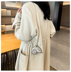 Silberne Umhängetasche in Schneckenform mit Metallkette an einem Model