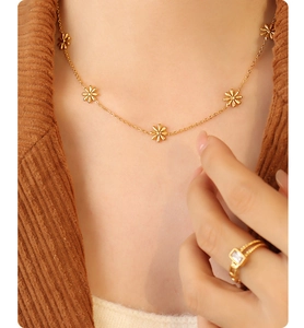 Detail of gold floral necklace with daisy charms on a model with corduroy jacket