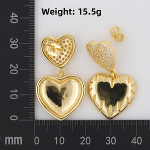 Detailed view of 15.5g gold heart-shaped double earrings on a scale ruler measuring grid