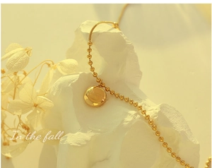 Détail macro d'un collier à billes dorées avec pendentif rond gravé du mot Lucky