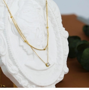 Detail of 18K gold plated double layer necklace with square zircon on classical bust