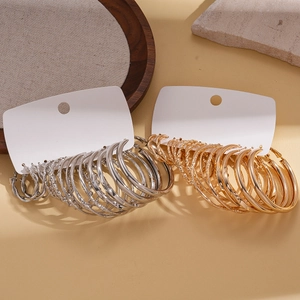 16-piece geometric gold and silver hoop earrings set on aesthetic stone and wood display