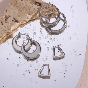 Detailed view of silver diamond-cut hoop earrings reflecting on water droplets surface
