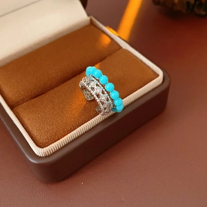 Vista dettagliata di un anello in argento traforato con perline turchesi in custodia