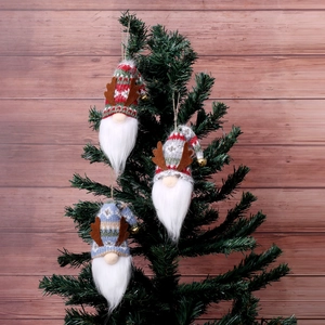 Three Christmas gnome ornaments with reindeer antlers hanging on a rustic wooden background