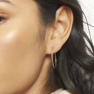 Polished gold large hoop earrings on model showing minimalist s925 silver needle style