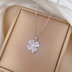 Close-up of silver clover pendant with white mother-of-pearl inlay and center crystal