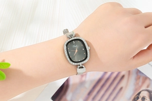 Close-up of elegant silver mesh strap watch with rhinestone bezel on female wrist
