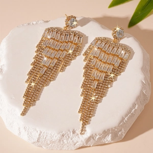 Vue détaillée de longues boucles d'oreilles pompons dorées avec cristaux étincelants