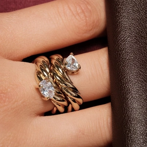 Golden stackable twisted rings with pear and marquise-cut zircon stones on model's hand