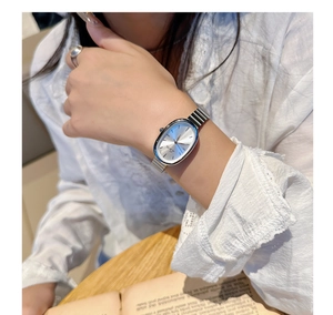 Close-up of a silver oval quartz watch with a sleek link bracelet on a female wrist