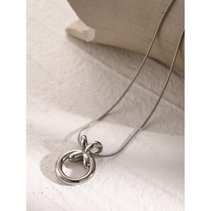Detail of silver stainless steel necklace with XO pendant on white textured background