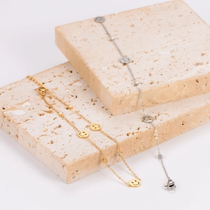 Minimalistische Smiley-Fußkettchen in Gold und Silber auf dekorativen Steinen