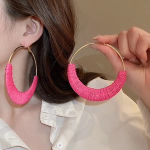 Close-up of oversized gold hoop earring with pink woven fabric wrap for a boho style