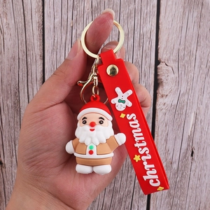 Detail of Santa Claus PVC keychain with red strap and golden metal hook held by hand