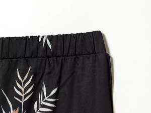 Detail of elastic waistband on black casual trousers with white leaf print pattern