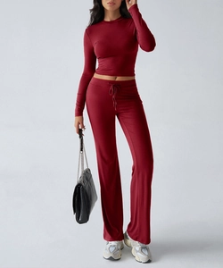Detail view of red long sleeve tight top and matching wide leg pants yoga set on model