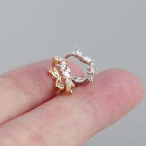 Detailed shot showing marquise-cut zircon stones on gold and silver hoop earrings