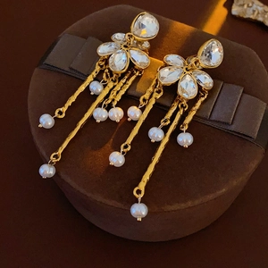 Detailed close-up of gold flower earrings with crystal accents and long pearl tassels
