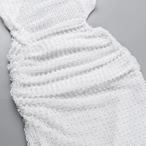Close-up of white dress showing intricate lace texture and pleated fabric layers