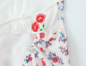 Close-up of intricate red floral embroidery and elastic pleated texture on white dress