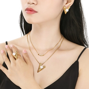 Detail of layered gold stainless steel jewelry set with pearls on a female model