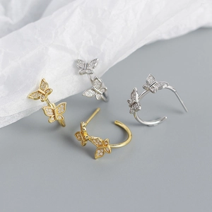 Makroaufnahme von Schmetterlings-Ohrsteckern in Silber und Gold mit funkelnden Zirkonia-Steinen