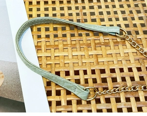Gros plan d'une bandoulière en cuir vert clair avec chaîne dorée et coutures détaillées