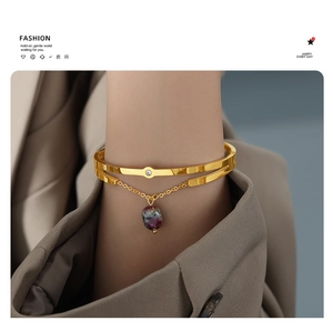 Close-up of golden double-layer bracelet with purple gemstone charm on model wrist