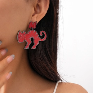 Macro shot of red enamel cat earrings with black metal trim worn by a model