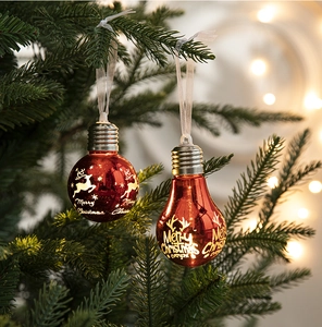 Close-up of red Christmas bulb ornament with white reindeer print on a pine tree branch