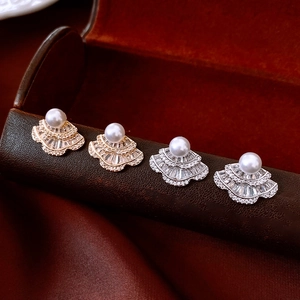 Macro shot of fan-shaped pearl earrings with cubic zirconia on a luxury leather box