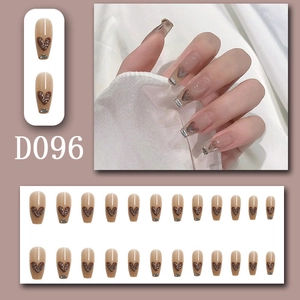 Detail of nude press-on nails featuring brown glitter hearts and silver trim design
