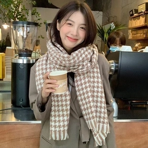 Close-up of brown and beige houndstooth scarf with fringe detail in warm cafe setting