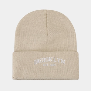 Detail of beige knit beanie featuring white Brooklyn Est 1634 embroidery text