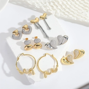 Golden and silver heart dangle earrings set displayed on white textured stone background