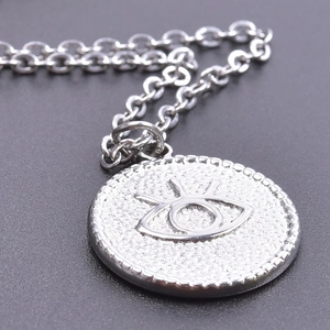 Macro shot of silver stainless steel necklace featuring a round devil's eye pendant charm