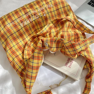 Top view of large plaid canvas tote with embroidery, next to a laptop on a white desk
