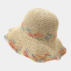 Close-up of woven straw texture with colorful rainbow striped detail on the sun hat