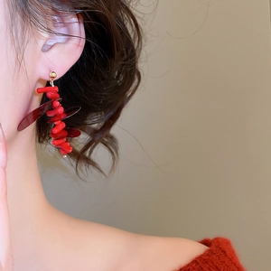 Macro detail of red sequin tassel earrings worn by a model in a red sweater