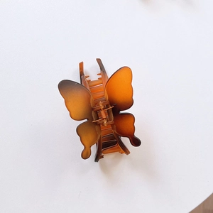 Detailed view of an amber butterfly hair claw clip with smooth resin finish