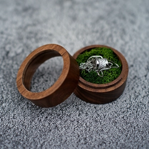 Detail of round wooden jewelry box with a silver necklace on green decorative moss base