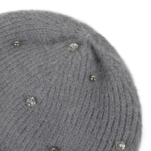 Détail du bonnet en maille grise avec des strass brillants et des rivets argentés