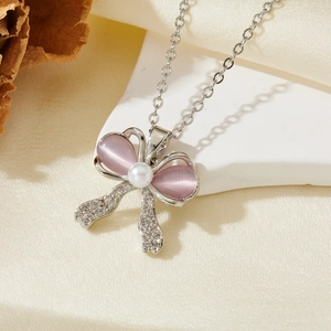 Détail du collier nœud avec pierres œil de chat mauves et perles sur pierre blanche