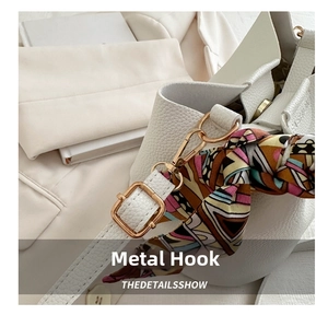 Close-up of white lychee leather texture with gold metal hook and printed silk scarf