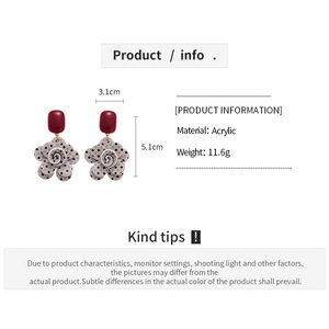 Macro detail of acrylic floral earrings with red rectangular studs and polka dot petals