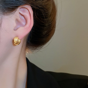 Detailed close-up of golden matte double-hoop earrings worn by a model
