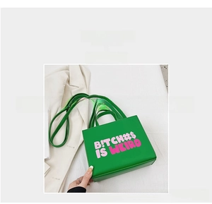 Detail of green rectangular handbag with pink and white typographic prints on leather