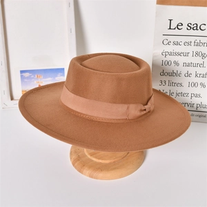 Detail view of a brown wool felt fedora with ribbon trim on a wooden display stand